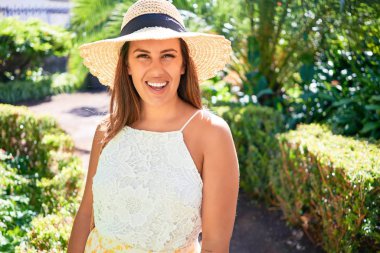 Güneşli bir yaz gününde yeşil parkta mutlu ve neşeli gülümseyen güzel bir kadın.