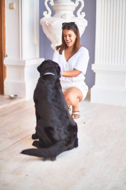 Terasta genç ve güzel bir kadın siyah labrador köpeğiyle oynuyor.