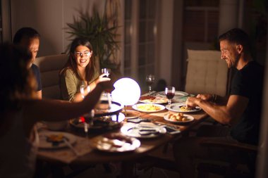 Güzel bir aile akşam yemeğinde terasta konuşuyor ve gülümsüyor