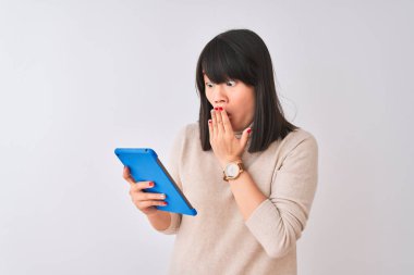 Güzel Çinli kadın mavi tablet kullanıyor. İzole edilmiş beyaz arka planda duruyor. Ağzı kapalı.