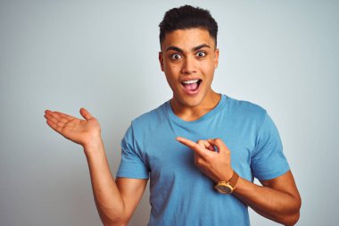 Mavi tişört giyen genç Brezilyalı adam izole edilmiş beyaz arka planda durup kameraya hayret ediyor ve gülümsüyor..