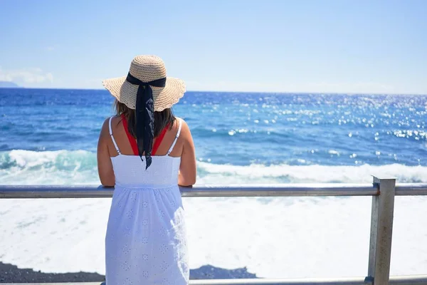 Young beautiful woman looking at the sea enjoying summer vacation at the beach