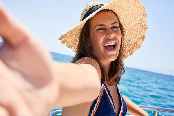 スマートフォンを使って自撮りをする若い美しい女性が笑顔で 休日の晴れた日にボートに乗って航海する — ストック写真