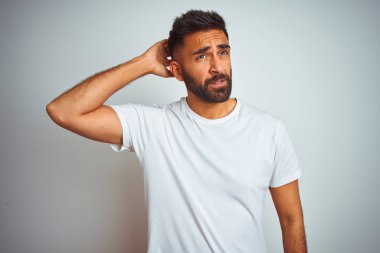 İzole edilmiş beyaz arka plan üzerinde duran ve soru soran genç Hintli bir adam. Şüpheyle kararsız, kafa kafaya düşünerek. Düşünceli kavram.