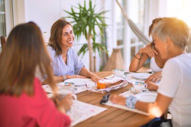 Genç ve güzel bir kız mutlu ve kendinden emin bir şekilde terasta oturmuş bir fincan kahve içiyor.