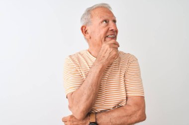 Üst düzey gri saçlı, çizgili tişört giyen, izole edilmiş beyaz arka planda duran, elleri çenesinde soru soran, düşünceli bir adam. Gülen ve düşünceli bir yüz. Şüphe kavramı.