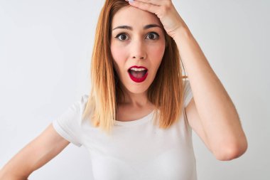 İzole edilmiş beyaz arka planda dikilen günlük tişört giyen güzel kızıl saçlı kadın elleri başının üstünde, utanç ve şaşkınlık dolu, sinirli ve hayal kırıklığına uğramış bir halde. Hata için korku ve üzüntü.