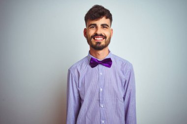 Mor gömlekli ve papyonlu genç bir adam izole edilmiş beyaz arka planda mutlu ve havalı bir gülümsemesi var. Şanslı kişi..