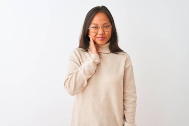 Balıkçı yaka kazak ve gözlük takan genç Çinli bir kadın diş ağrısı ya da diş ağrısı yüzünden ağza dokunuyor. Dişçi konsepti.