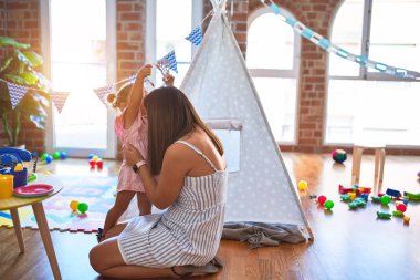 Genç, güzel öğretmen ve bebek anaokulunda prenses Cown 'la oynuyorlar.