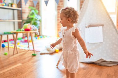 Renkli oyun odasında beyaz güzel bir bebek oyuncaklarla oynuyor. Anaokulunda mutlu ve şen şakrak.