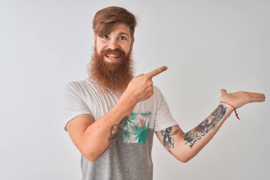İzole edilmiş beyaz arka plan üzerinde duran kızıl saçlı genç adam kameraya hayret ediyor ve gülümsüyor..