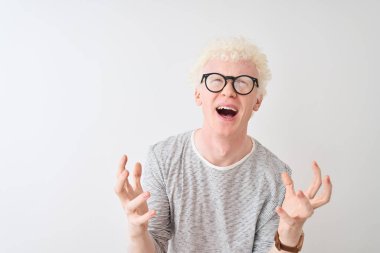 Genç albino sarışın adam çizgili tişört ve gözlüklerle izole edilmiş beyaz arka planda çılgınca bağırıyor ve agresif bir ifade ve kolla bağırıyor. Hayal kırıklığı konsepti.