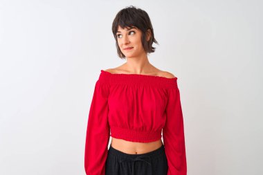 Kırmızı yaz tişörtü giyen genç ve güzel bir kadın izole edilmiş beyaz arka planda duruyor gülümsüyor ve başka tarafa bakıyor..