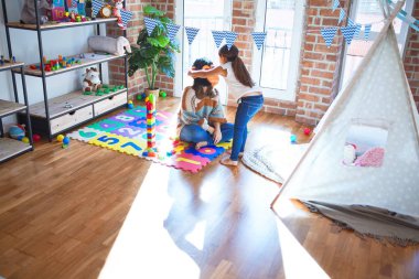 Anaokulunda bir sürü oyuncağın etrafında maymun maskesiyle oynayan güzel öğretmen ve bebek.