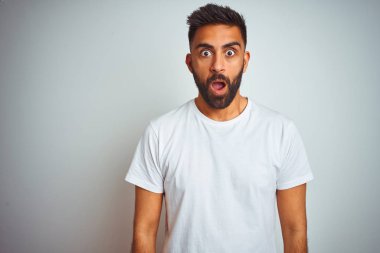 İzole edilmiş beyaz arka plan üzerinde duran genç Hintli adam şaşkınlık ve şaşkınlık ifadesi, korku ve heyecan dolu yüz ifadesiyle dehşete düşmüş ve şok olmuştu..