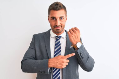 Takım elbiseli ve kravatlı genç bir iş adamı. Aceleyle saate, sabırsızlığa ve rahat bir ifadeyle kameraya bakıyor.