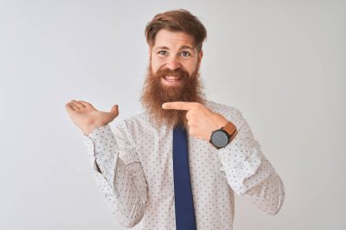 İzole edilmiş beyaz arka planda duran genç kızıl saçlı işadamı kameraya hayret ediyor ve gülümsüyor..