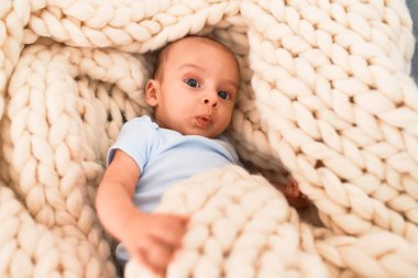 Evdeki kanepede battaniyenin üzerine uzanmış sevimli bir bebek. Yeni doğmuş bebek rahatlıyor ve dinleniyor.