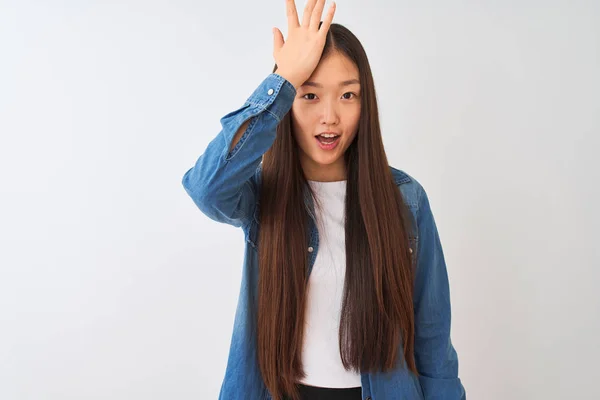 年轻的中国女人穿着斜纹棉布衬衫站在孤立的白色背景上 对手头上的错误感到惊讶 记住错误 记性差 — 图库照片