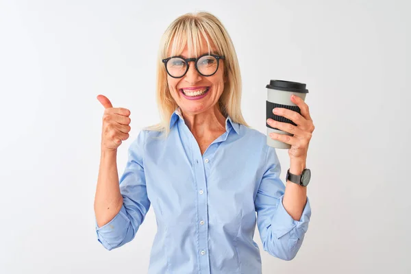 中年女商人戴着眼镜 在与世隔绝的白色背景下喝咖啡 开心地笑着做个好手势 用手指竖起大拇指 很好的标志 — 图库照片