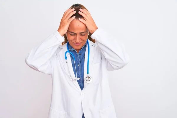 中年の成熟した医師の女性は 痛みや片頭痛のために必死に頭痛やストレスに苦しんで孤立した背景に聴診器を身に着けています 手を頭に — ストック写真