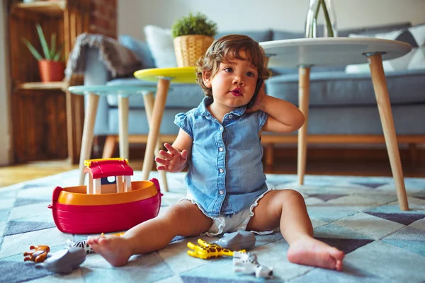 Schönes Kleinkind Das Auf Dem Teppich Sitzt Und Mit Dem — Stockfoto