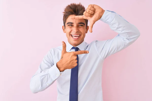若いハンサムなビジネスマンがシャツを着て 幸せな顔をした手と指でフレームを作る独立したピンクの背景笑顔の上に立ってネクタイ 創造性と写真の概念 — ストック写真