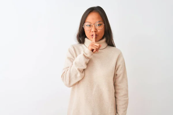年轻的中国女人穿着高领毛衣和眼镜 站在孤立的白色背景上 要求安静 手指放在嘴唇上 沉默和秘密概念 — 图库照片