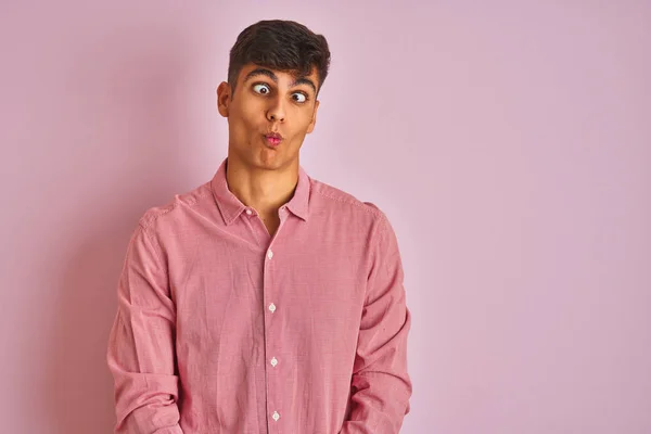 年轻的印度男子穿着雅致的衬衫 站在孤立的粉色背景之上 用嘴唇 疯狂和滑稽的姿势做鱼脸 有趣的表达方式 — 图库照片