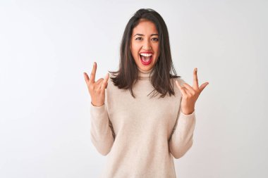 Balıkçı yaka kazak giyen güzel Çinli kadın izole edilmiş beyaz arka plan üzerinde duruyor çılgın bir ifadeyle elleri havada rock sembolü yapıyor diye bağırıyor. Müzik yıldızı. Ağır müzik konsepti.