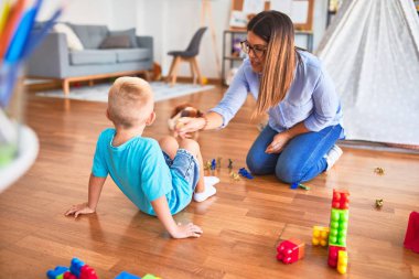 Genç beyaz çocuk öğretmeniyle oyun okulunda oynuyor. Oyuncak askerlerle oyuncak odasında oynamak.