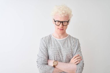 İzole edilmiş beyaz arka plan üzerinde çizgili tişört ve gözlük takan genç, sarışın adam şüpheci ve gergin, yüzünde çapraz kollu tasvip etmeyen bir ifade var. Negatif kişi.