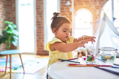 Anaokulunun masasında çikolata renkli toplarla oynayan güzel çocuk.