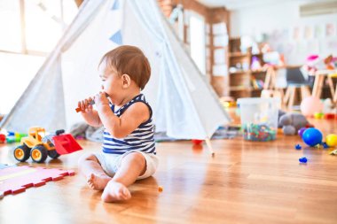Anaokulunda bir sürü oyuncakla oynayan sevimli bir çocuk.