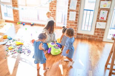 Güzel öğretmen ve bir grup çocuk anaokulunda bir sürü oyuncakla oynuyorlar.