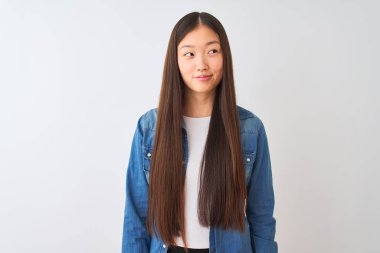 Kot gömlek giyen genç Çinli kadın izole edilmiş beyaz arka planda duruyor gülümsüyor ve başka tarafa bakıyor..