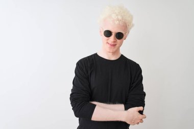 Siyah tişört giyen ve güneş gözlüklü genç albino adam izole edilmiş beyaz arka planda durup kameraya bakarken kollarını kavuşturup gülümsüyor. Pozitif kişi.