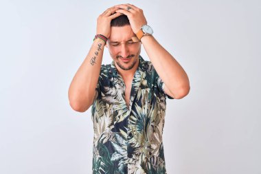 Hawaii tişörtü giyen yakışıklı genç bir adam izole bir arka planda baş ağrısı ve stres yüzünden acı çekiyor çünkü acı ve migren. Ellerini başının üstüne koy..
