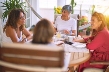 Genç ve güzel bir kız mutlu ve kendinden emin bir şekilde terasta oturmuş bir fincan kahve içiyor.