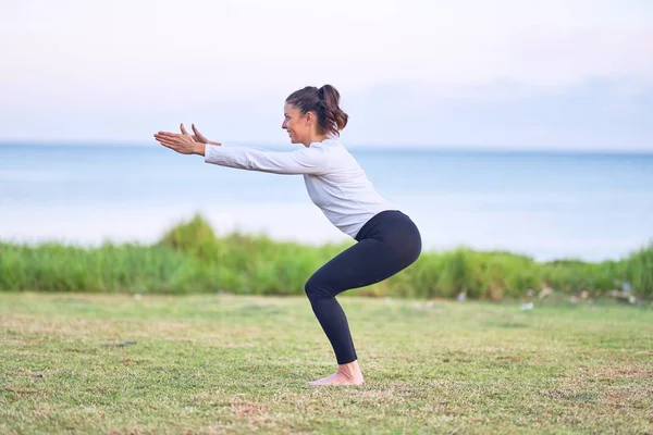 Young beautiful sportwoman practicing yoga. Coach teaching chair pose at park