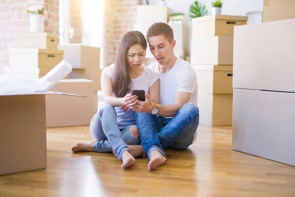 Hermosa Pareja Sentada Suelo Usando Teléfono Inteligente Nuevo Hogar Alrededor — Foto de Stock