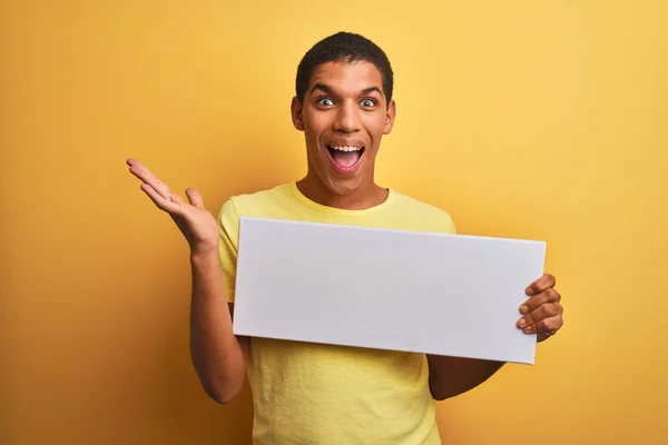 Homem Árabe Bonito Jovem Segurando Banner Sobre Fundo Amarelo Isolado — Fotografia de Stock