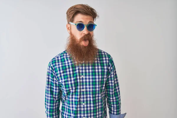 年轻红头发的爱尔兰男人穿着休闲服 戴着太阳镜 戴在孤立的白色背景上 带着滑稽的表情伸出舌头 情感概念 — 图库照片