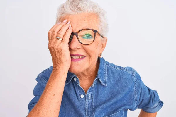 头发灰白的老年妇女 身穿斜纹棉布衬衫 戴着眼镜 用一只手捂住一只眼睛 脸上挂着自信的微笑 情绪令人惊讶 — 图库照片