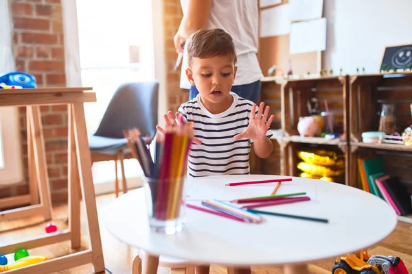 幼稚園で色鉛筆を使って絵を描く美しい先生と幼児 — ストック写真