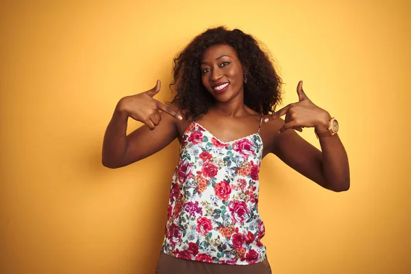 アフリカ系アメリカ人女性の花の夏のTシャツを身に着けています孤立した黄色の背景の上に笑顔で自信を持って見えます 誇りと幸せ指で自分自身を指して — ストック写真