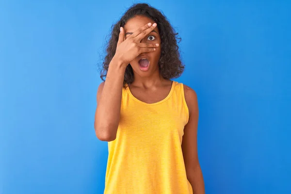 Jovem Brasileira Vestindo Camiseta Amarela Sobre Fundo Azul Isolado Espreitando — Fotografia de Stock