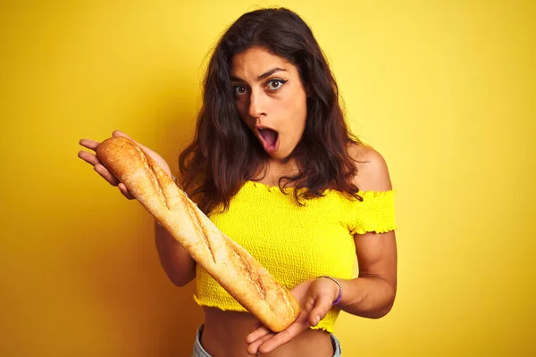 Jovem Bela Padeiro Segurando Pão Sobre Fundo Amarelo Isolado Assustado — Fotografia de Stock