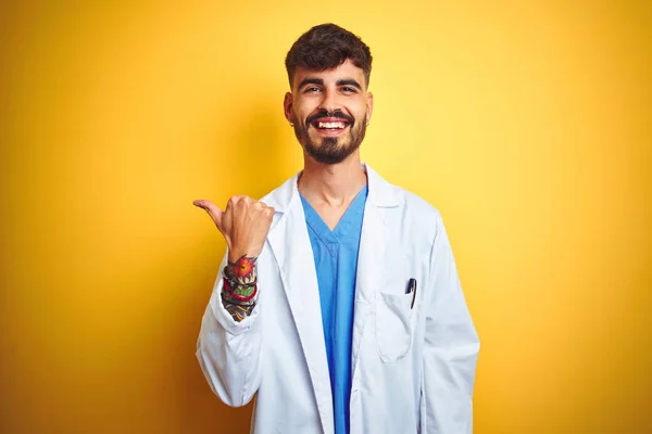 Młody Lekarz Tatuażem Stojący Nad Odizolowanym Żółtym Tłem Uśmiechający Się — Zdjęcie stockowe